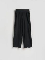 Bawełniane spodnie z falbanką - czarny. Czarne spodnie materiałowe damskie Reserved, l, bez wzorów, z bawełny. Za 99.99 zł.