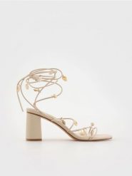 Sandały z ozdobnymi muszelkami - kremowy. Białe sandały damskie Reserved, bez wzorów, ze skóry, bez obcasa, na obcasie, bez zapięcia. W wyprzedaży za 79.99 zł.