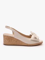 Kremowe sandały na koturnie z kokardą. Brązowe sandały damskie Ryłko, bez wzorów, ze skóry, bez obcasa, na koturnie, bez zapięcia. Za 399.99 zł.