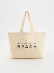 Płócienna torebka shopper - złamana biel. Torebki shopper damskie Reserved, bez wzorów, z bawełny, z nadrukiem, bez dodatków. Za 49.99 zł.