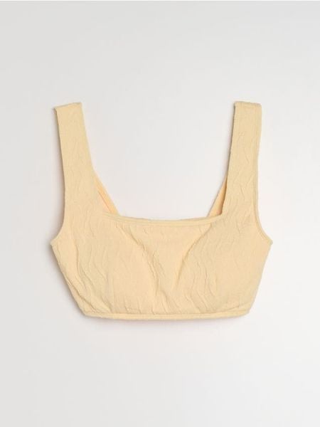 Strukturalna góra od bikini typu beach top - kremowy. Białe bikini damskie Sinsay, l, bez wzorów, bez kołnierzyka, bez ramiączek. Za 25.99 zł.