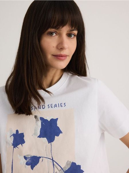 T-shirt z nadrukiem - biały. Białe t-shirty damskie Reserved, l, bez wzorów, z bawełny, bez kołnierzyka. W wyprzedaży za 25.99 zł.