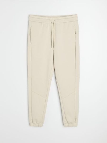 Spodnie tapered fit Active - kremowy. Białe spodnie sportowe męskie Sinsay, l, bez wzorów, na fitness i siłownię. Za 59.99 zł.
