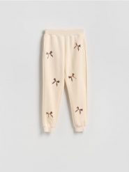 Spodnie dresowe z aplikacjami - złamana biel. Spodnie dresowe damskie Reserved, l, z aplikacjami, z bawełny. Za 99.99 zł.