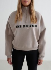 Damska bluza dresowa z półzamkiem, drapana, luźna Varsity ciemna glina. Brązowe bluzy damskie Aim'n, m, bez wzorów, z bawełny, bez kaptura, na fitness i siłownię. Za 339.00 zł.