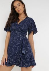 Granatowa Sukienka Devizo. Niebieskie sukienki damskie Born2be, s, bez wzorów, z materiału, bez kołnierzyka, bez ramiączek, mini, kopertowe. Za 29.99 zł.