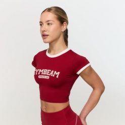 Koszulka damska fitness slim czerwona Varsity. Czerwone koszulki sportowe damskie GYMBEAM, l, bez wzorów, z materiału, bez kołnierzyka, bez ramiączek, na fitness i siłownię. Za 88.90 zł.