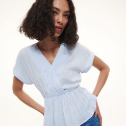 Bluzka z wiązaniem w pasie - jasnoniebieski. Niebieskie bluzki damskie Reserved, bez wzorów, z tkaniny, bez kołnierzyka, bez ramiączek. W wyprzedaży za 22.99 zł.