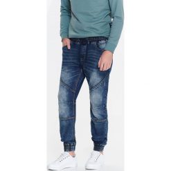SPODNIE MĘSKIE TYPU JOGGER Z DZIANINY IMITUJĄCEJ JEANS. Spodnie materiałowe męskie marki TOP SECRET. W wyprzedaży za 89.99 zł.