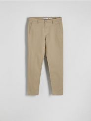 Spodnie chino slim fit - beżowy. Brązowe spodnie materiałowe męskie Reserved, bez wzorów, z bawełny. W wyprzedaży za 89.99 zł.
