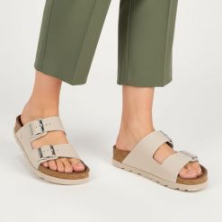 Klapki Damskie Rieker, cholewka skóra naturalna gładka dwa szerokie paski z metalowymi klamrami odkryte palce regulowane zapięcie. Szare klapki damskie Rieker, bez wzorów, ze skóry, wakacyjne. Za 269.90 zł.