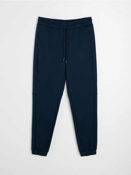 Spodnie tapered fit Active - granatowy. Niebieskie spodnie sportowe męskie Sinsay, l, bez wzorów, na fitness i siłownię. Za 59.99 zł.