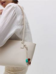 Torebka shopper z zawieszką - złamana biel. Torebki shopper damskie Reserved, bez wzorów, ze skóry, bez dodatków. W wyprzedaży za 79.99 zł.