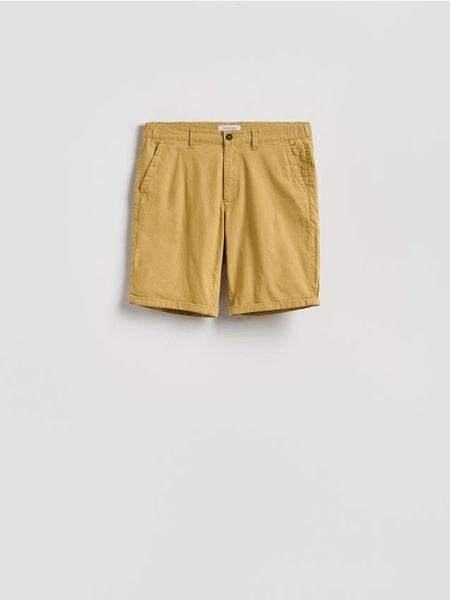 Bawełniane szorty chino - bursztynowy. Pomarańczowe spodnie materiałowe męskie Reserved, l, bez wzorów, z bawełny. Za 119.99 zł.
