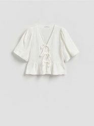 Muślinowa bluzka z wiązaniem - biały. Białe bluzki damskie Reserved, l, bez wzorów, z bawełny, klasyczne, bez kołnierzyka, bez ramiączek. Za 99.99 zł.