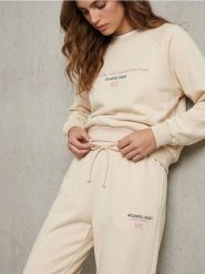 Spodnie regular jogger fleece z hafotwanym napisem NYC - kremowy. Białe spodnie materiałowe damskie Sinsay, l, bez wzorów. Za 39.99 zł.