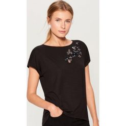Koszulka z aplikacją - Czarny. Czarne t-shirty damskie Mohito, z aplikacjami. W wyprzedaży za 39.99 zł.