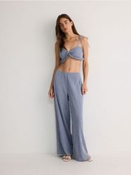 Spodnie ze strukturalnej tkaniny - granatowy. Niebieskie spodnie materiałowe damskie Reserved, l, bez wzorów, z bawełny. W wyprzedaży za 69.99 zł.