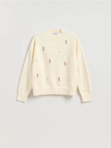 Sweter z ozdobnymi aplikacjami - kremowy. Białe swetry damskie Reserved, l, z aplikacjami, z dzianiny, bez kołnierzyka, bez ramiączek, bez kaptura. Za 139.99 zł.