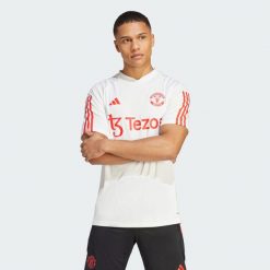 Koszulka piłkarska męska Adidas Manchester United Tiro 23. Białe koszulki sportowe męskie Adidas, l, bez wzorów, z materiału, bez kołnierzyka, bez ramiączek, do piłki nożnej. Za 246.35 zł.
