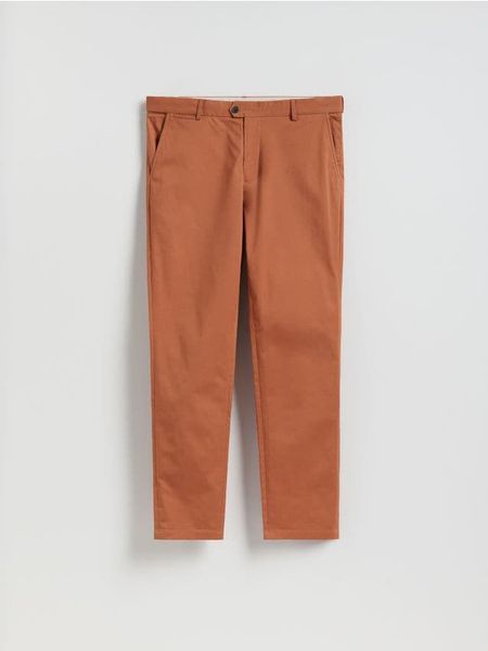 Spodnie chino slim fit - karminowy. Czerwone spodnie materiałowe męskie Reserved, bez wzorów, z bawełny. W wyprzedaży za 89.99 zł.