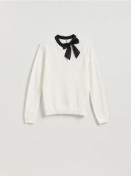 Sweter z ozdobną kokardą - kremowy. Białe swetry damskie Reserved, l, bez wzorów, z dzianiny, bez kołnierzyka, bez ramiączek, bez kaptura. Za 109.99 zł.
