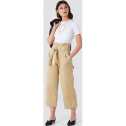 NA-KD Trend Szerokie spodnie bawełniane z wiązaniem w talii - Beige. Spodnie materiałowe damskie marki NA-KD Trend. W wyprzedaży za 101.47 zł.