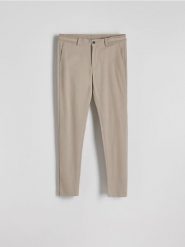 Spodnie chino slim fit - beżowy. Brązowe spodnie materiałowe męskie Reserved, bez wzorów, z tkaniny. Za 159.99 zł.