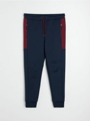 Sportowe spodnie jogger z kontrastowymi panelami i kieszeniami na zamek - granatowy. Niebieskie spodnie sportowe męskie Sinsay, l, bez wzorów, na fitness i siłownię. Za 69.99 zł.