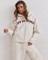 Damska bluza zapinana na zamek z kapturem Varsity kremowa. Białe bluzy damskie Aim'n, l, bez wzorów, z bawełny, z kapturem, na fitness i siłownię. Za 388.00 zł.