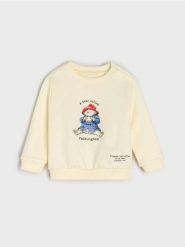 Bawełniana bluza z nadrukiem Paddington - kremowy. Białe bluzy dla niemowląt Sinsay, bez wzorów, z bawełny, bez ramiączek, bez kaptura. Za 13.99 zł.