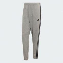 Spodnie Essentials z tkaniny frotté z 3 paskami i zwężanymi nogawkami. Białe spodnie sportowe męskie Adidas, l, bez wzorów, z bawełny, na fitness i siłownię. Za 219.00 zł.