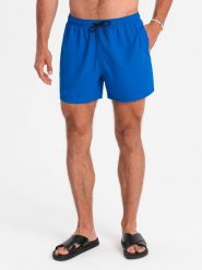 Neonowe męskie szorty kąpielowe z efektem magic print – niebieskie V3 - Rozmiar: XXL. Niebieskie kąpielówki męskie Ombre Clothing, m, bez wzorów, z poliesteru, krótkie, do pływania. W wyprzedaży za 79.99 zł.