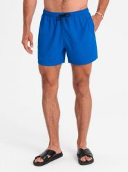 Neonowe męskie szorty kąpielowe z efektem magic print – niebieskie V3. Niebieskie kąpielówki męskie Ombre Clothing, m, bez wzorów, z poliesteru, krótkie, do pływania. W wyprzedaży za 79.99 zł.