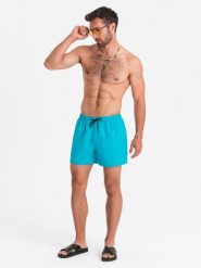 Neonowe szorty męskie kąpielowe z efektem magic print – turkusowe V2. Niebieskie kąpielówki męskie Ombre Clothing, m, bez wzorów, z poliesteru, krótkie, do pływania. W wyprzedaży za 79.99 zł.