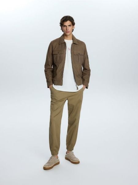 Spodnie jogger slim fit - beżowy. Brązowe spodnie materiałowe męskie Reserved, l, bez wzorów, z tkaniny. Za 119.99 zł.